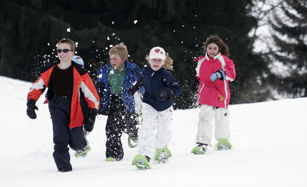 Indumenti sportivi: Sudare per vincere Un gruppo di bambini che indossano abiti invernali e racchette da sci ai piedi corrono nella neve