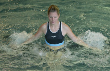 Fitness in acqua: L’acqua fa miracoli Una donna è in piedi in acqua poco profonda e esegue dei movimenti a mulinello con le braccia.