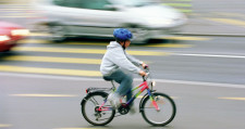Kind auf befahrener Strasse mit Fahrrad.