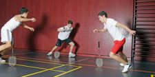 Drei Jugendliche mit Badmintonschlägern versuchen, diese im Kreis nicht fallen zu lassen.
