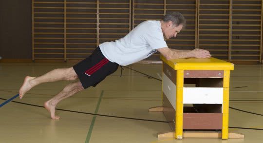 Un adulte effectue un exercice de renforcement en appui sur un banc.
