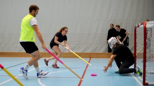 Jung Frauen und Männer beim Donut Hockey Spiel vor dem Tor.