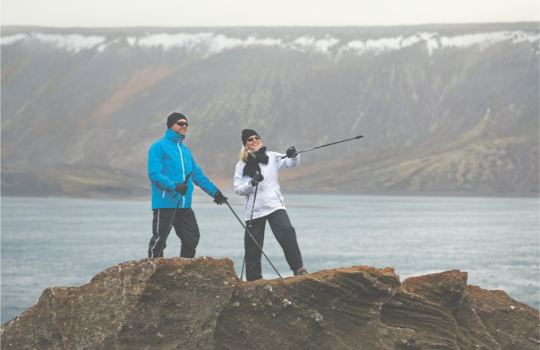 Un uomo e una donna in abiti sportivi invernali durante un allenamento di Nordic walking