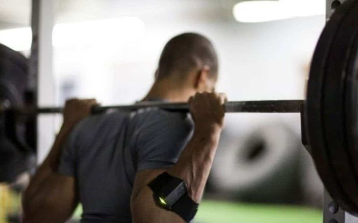 Mann beim Hanteltraining mit Geschwindigkeitsmesser am Arm.