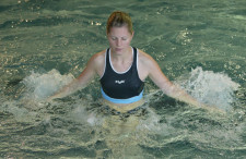 Una donna è in piedi in acqua poco profonda e esegue dei movimenti a mulinello con le braccia.