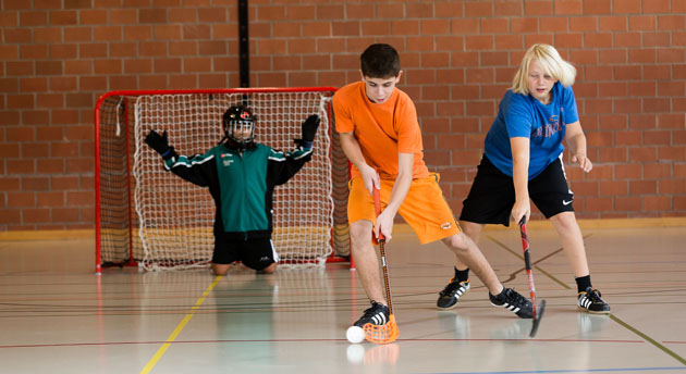 Unihockey: Découvrir en jouant Un enfant essaie de se défaire du marquage d'un défenseur pour tirer au but.