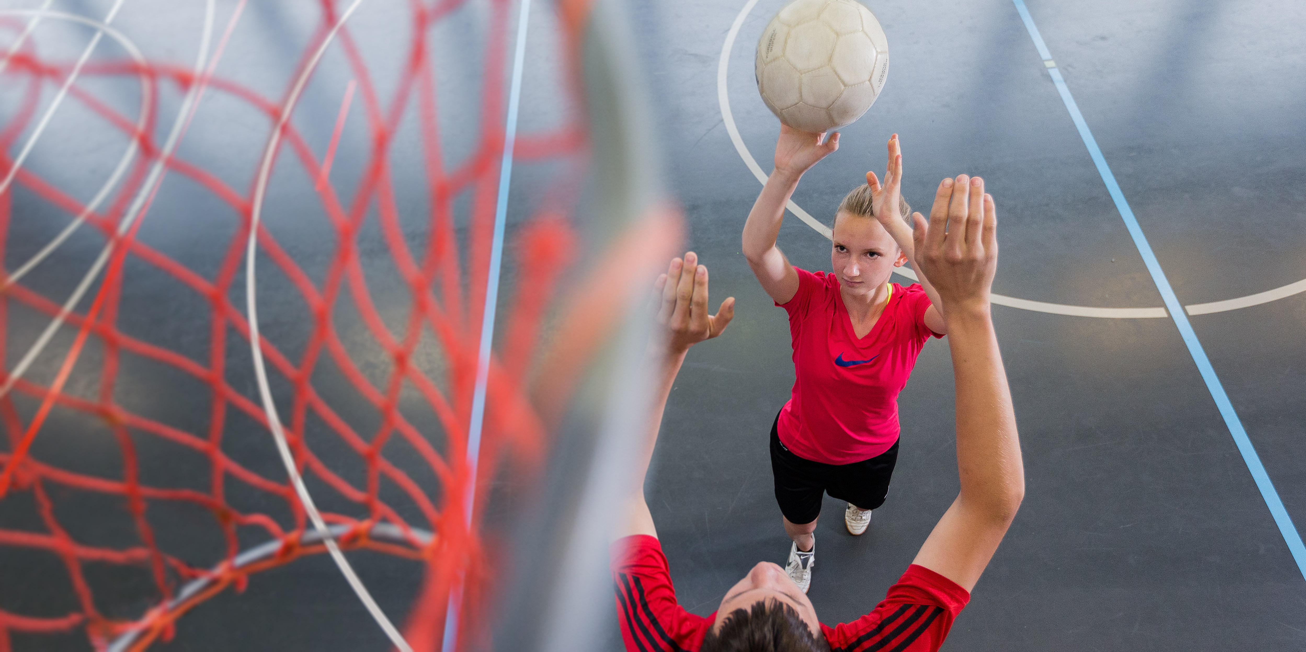 Foto: Spielerin versucht einen Korbwurf während ein Spieler verteidigt.