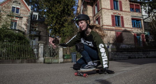 Foto: una ragazza scende lungo una strada di un quartiere residenziale sul suo longboard