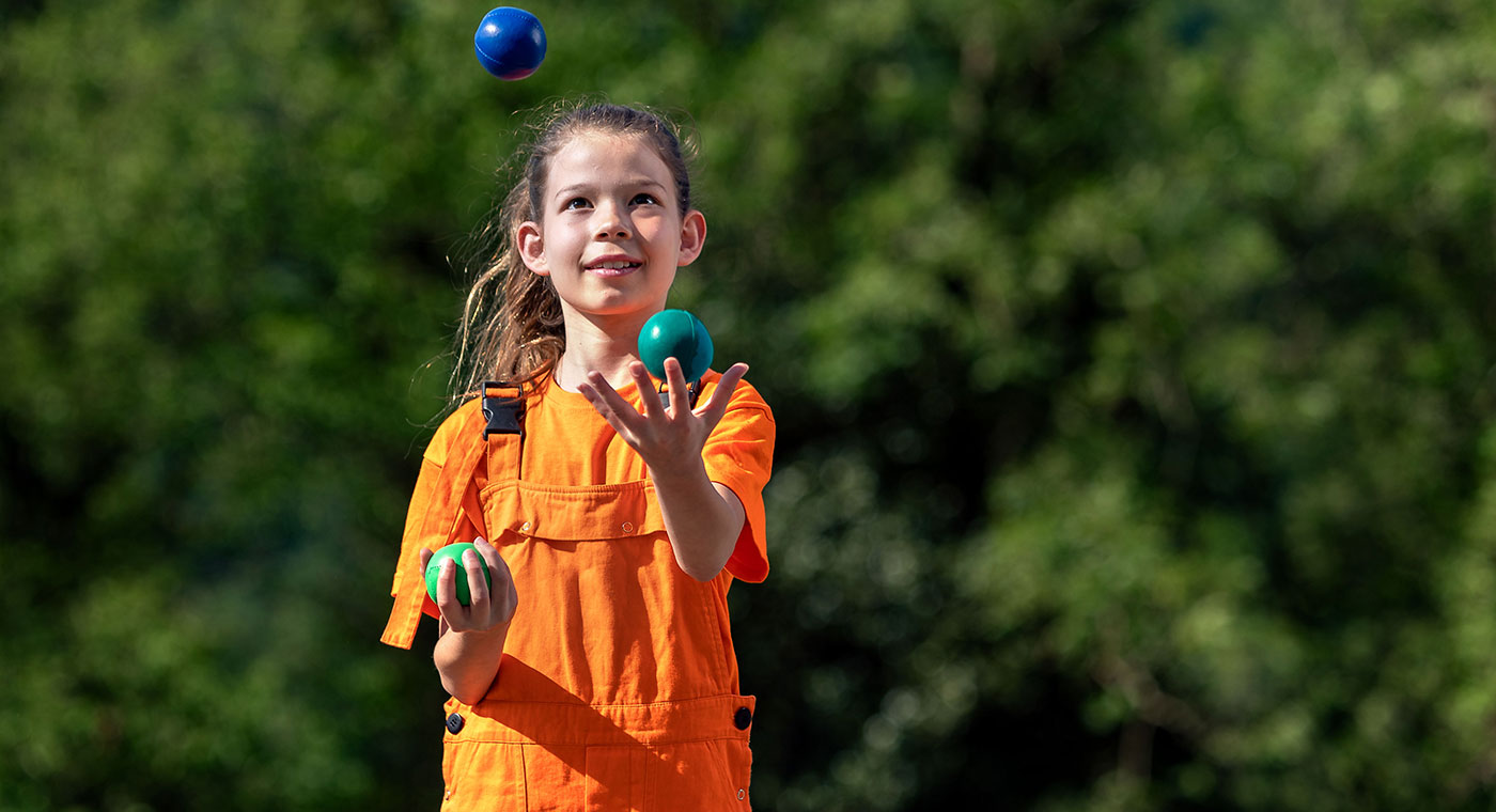 Foto: Ein Mädchen jongliert mit drei farbigen Bällen