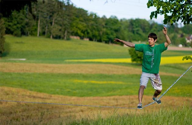 Junger Mann beim Balancieren auf einer Slackline Outdoor.